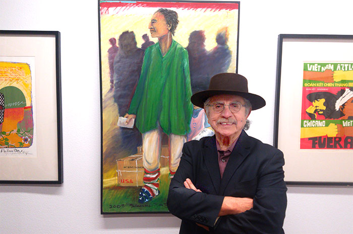 Malaquias Montoya stands in front of his paintings during exhibition at M Street Gallery