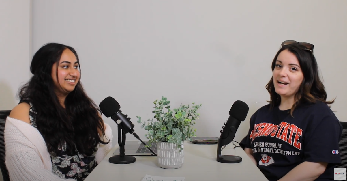 Photo of two people sitting across from each other for a podcast recording and smiling 