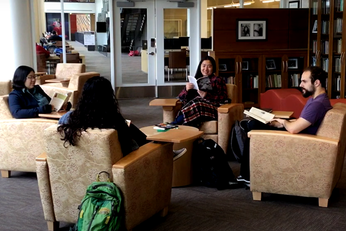 Four students sit in comfy chairs in a circle inside the Levine Reading Room.