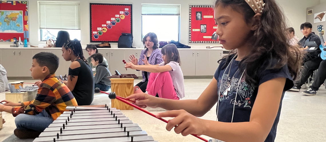 A young girl plays a xylophone in a music education training course.